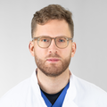 Portraitfoto von Johannes Mang: Mann mit Bart und Brille in weißem Arztkittel