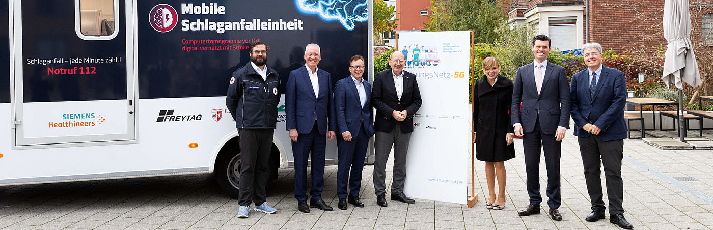 Gruppenfoto vor Rettungsfahrzeug und großem Aufsteller zum Thema 5G